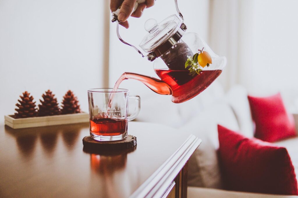 Pouring herbal tea from a glass teapot into a cup.