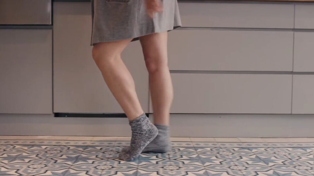 Person walking in grey socks on a patterned floor, captured through a Biteable video maker.