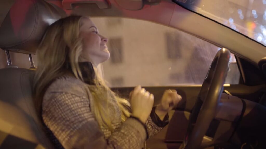 A woman smiling and dancing to music while creating a Biteable video at night.